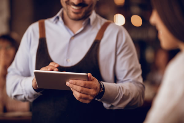 Waiter sedang mencatat pesanan tamu menggunakan tablet